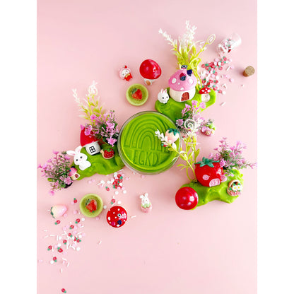 Earth Grown KidDoughs Bunny Berry Village KidDough Sensory Play Kit on a pink background. Jar of green KidDough in the middle of the picture with play pieces scattered all around it.
