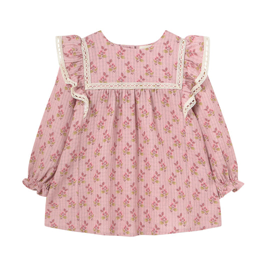 Isquia Dress from Cozmo. Pink long-sleeved dress with smocked cuffs and all-over floral print for babies. The dress has lace detailed shoulder ruffles and yokes.