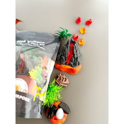 Toy volcano with lava, palm trees, lava acrylics and rocks on red/orange marbled KidDough and the right side of the EGKD Dino Sensory KidDough Play Kit packaging on a grey background.
