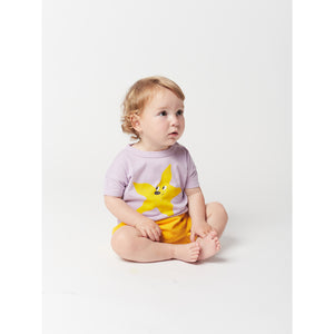 yellow starfish print on front on a lavender t-shirt with short sleeves and dropped shoulder and shoulder snap fastening from bobo choses for babies and toddlers